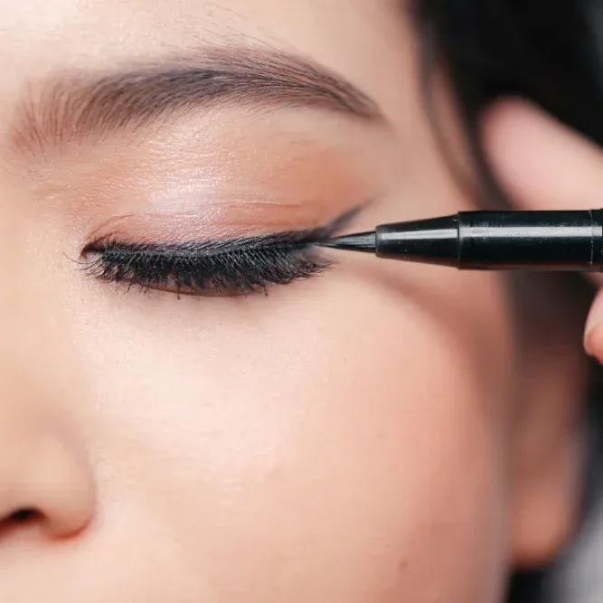 Close-up of a woman applying gel eyeliner above her natural lash line.