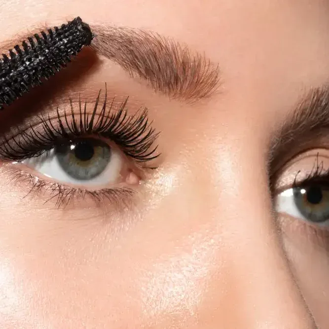Woman applying mascara to her lower natural lashes with a wand.
