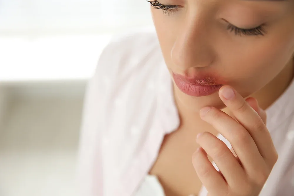 A woman with a poor lip tattoo result touches her irritated lips, illustrating the risks and potential complications of choosing a cheap service.
