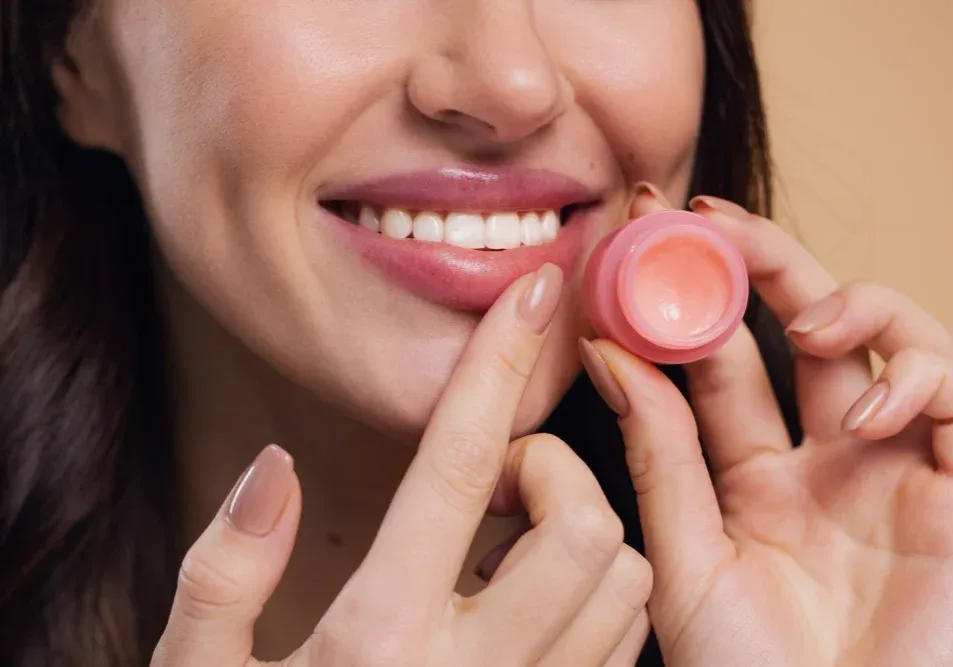 Client applies pink lip balm with fingers following wet healing method for better pigment retention