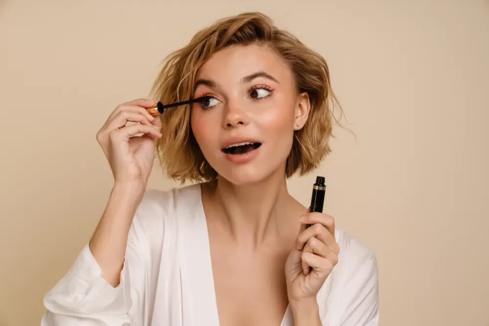 Confident woman applying mascara to her lashes.