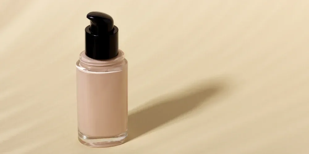 Bottle of liquid foundation checked for ingredients compatible with lash adhesive.