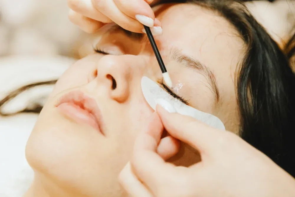 Close-up of a client's eye as a technician cleanses the remaining remover and adhesive from the natural lashes.