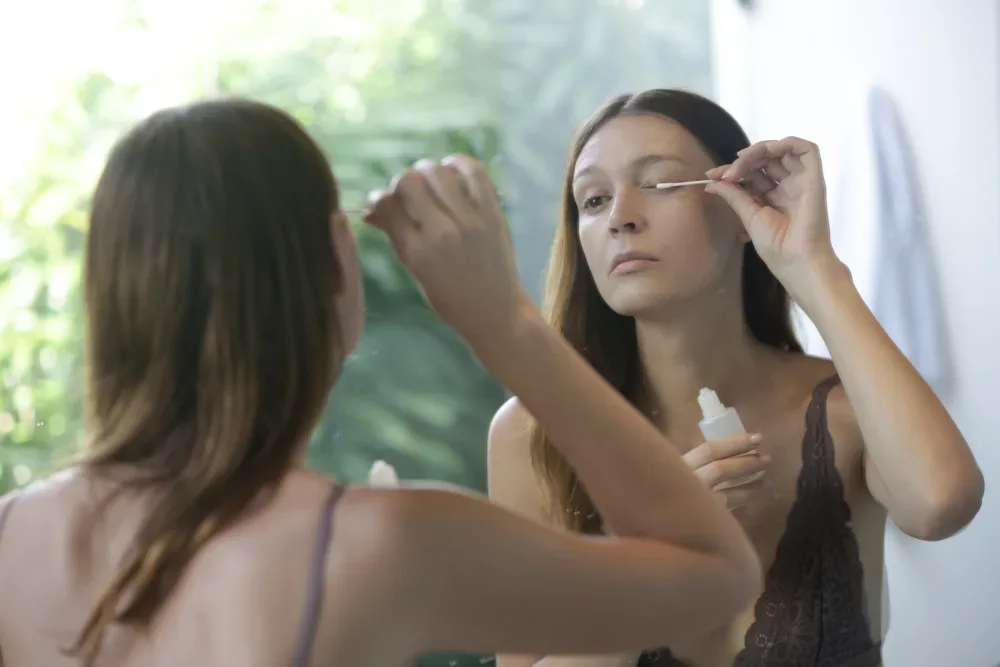 Woman attempting to remove her eyelash extensions at home.
