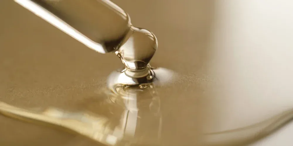 A drop of serum from a glass dropper, illustrating the topic of lash serum market regulation and FDA-approved ingredients.