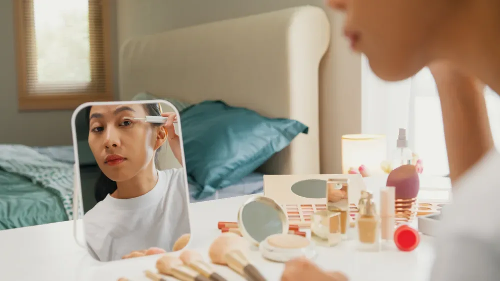 A woman examines her eyelashes in a mirror, illustrating the realistic expectations and timeframe for results from effective serums.