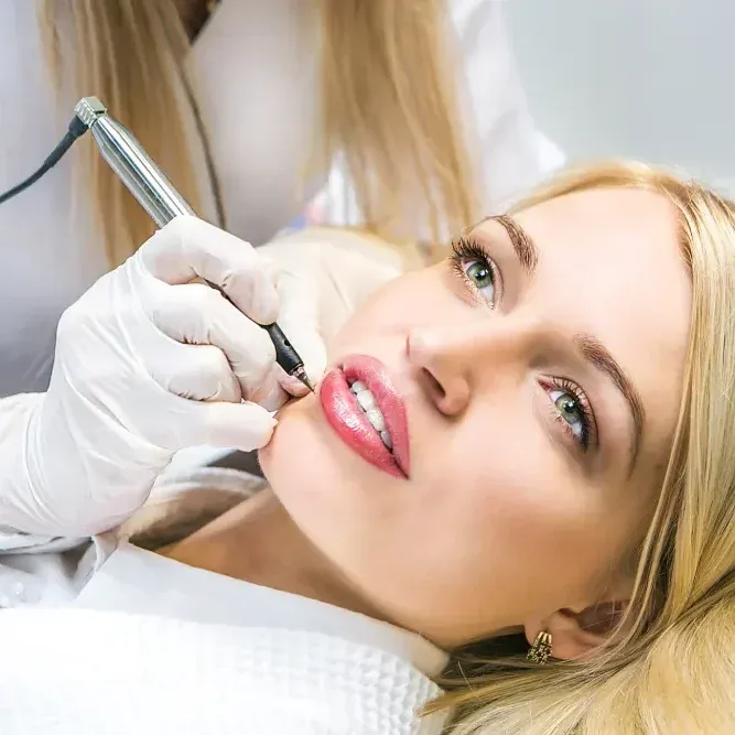A technician uses a tattoo machine to define the lip shape and add color, demonstrating the "your lips, only better" result of lip blushing.