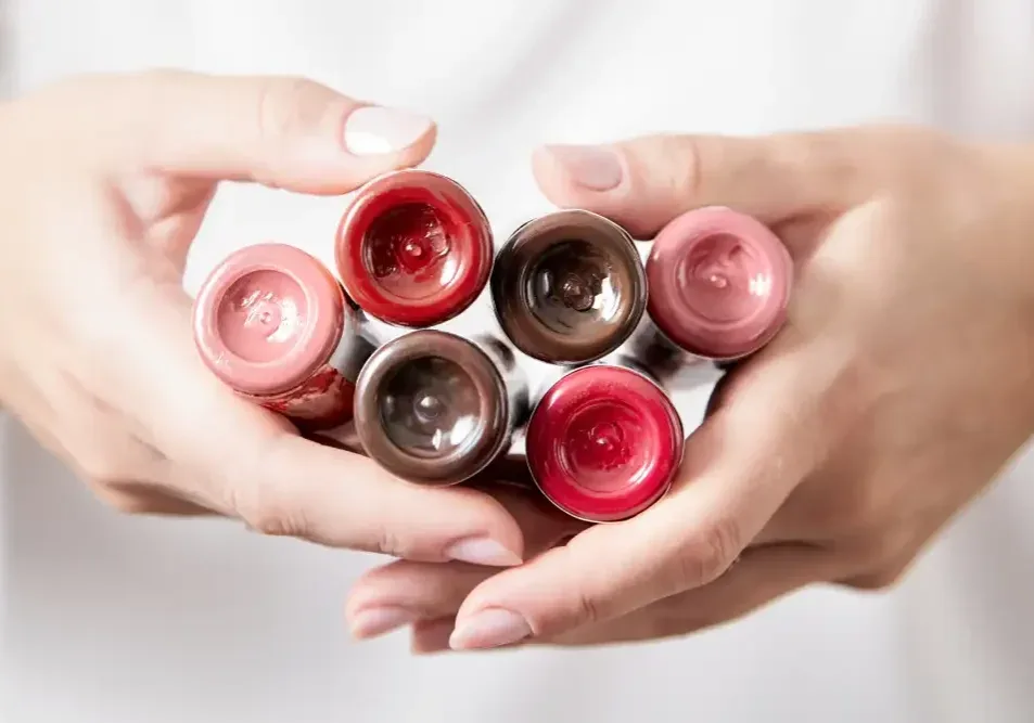 A woman's hands hold a collection of various lip tattoo pigments, illustrating the importance of pigment quality for safety and durability.