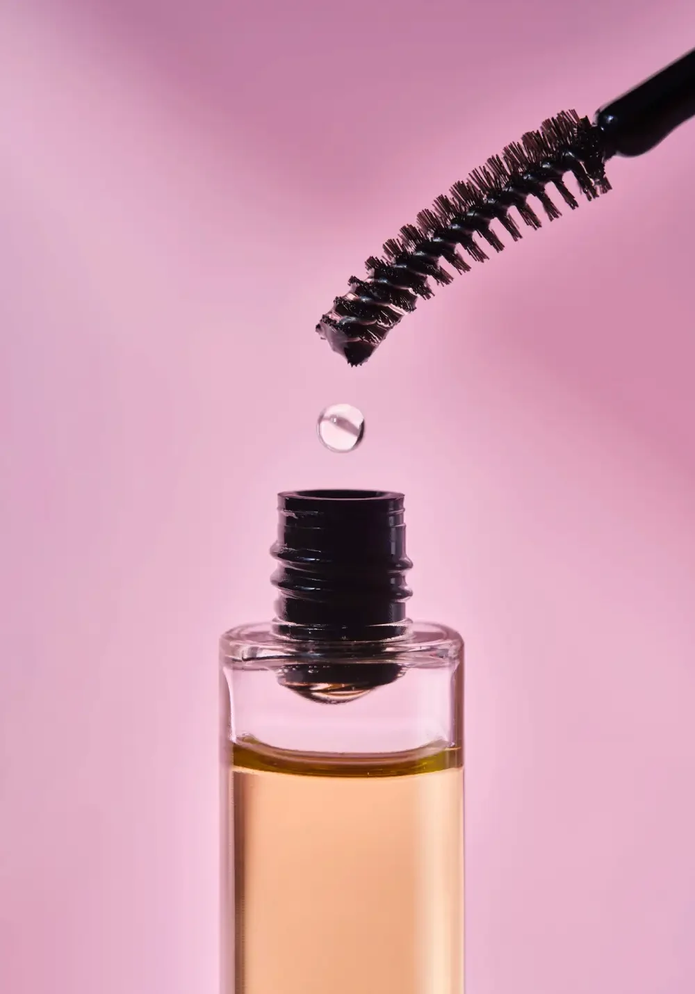 Key Ingredients in Eyelash Serums A drop of liquid on an applicator wand over a bottle, representing the key ingredients found inside eyelash serums.