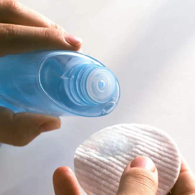 A bottle of oil-free micellar water and lint-free cotton pads, ready for the gentle removal of eye makeup.