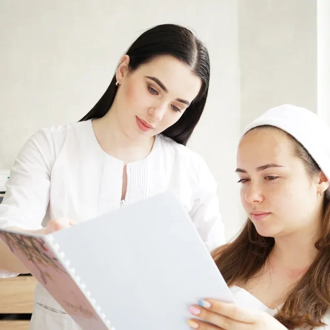 A technician shows a client a document, clarifying the pricing policy for corrections and adjustments to the permanent makeup.