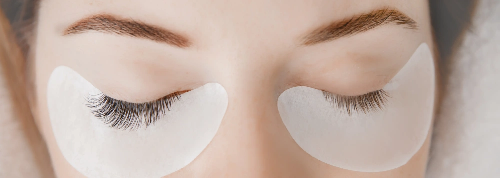 A client with under-eye pads applied, prepared for a full set of classic eyelash extensions.