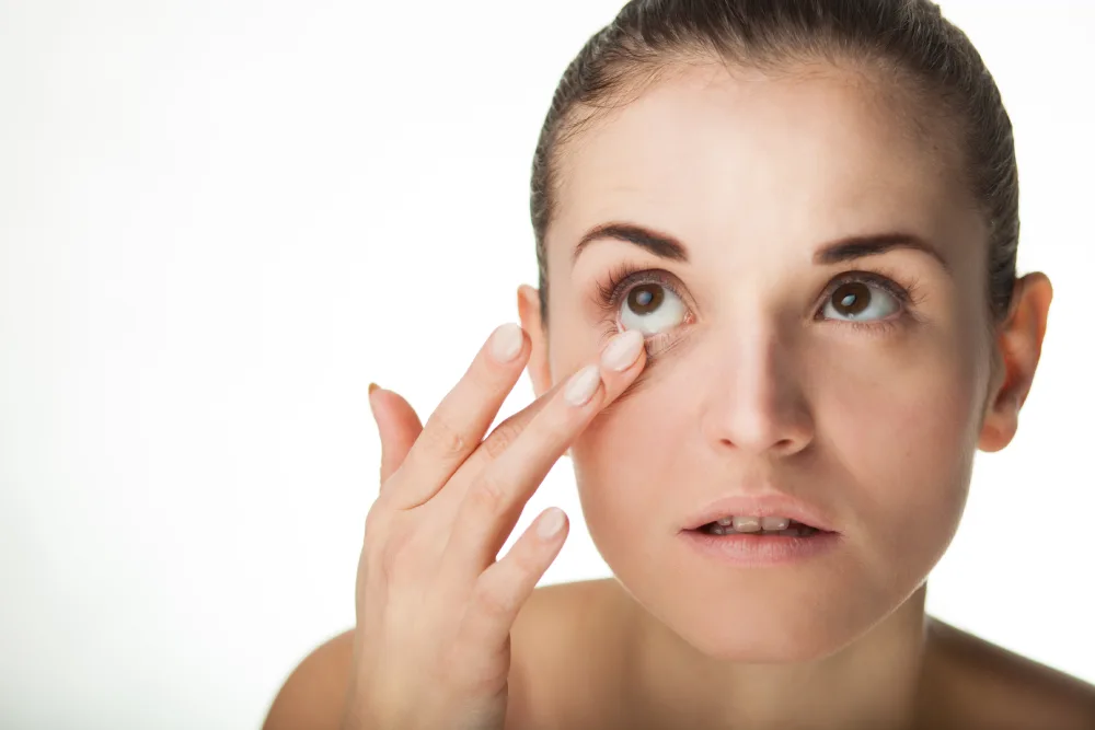 Myth: Do Extensions Ruin Natural Lashes? A woman inspects her eye with concern, representing the common myth that eyelash extensions ruin natural lashes.