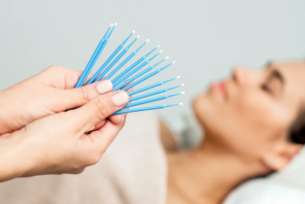 A technician holds a fan of new, disposable micro-brushes, emphasizing the importance of proper hygiene standards.