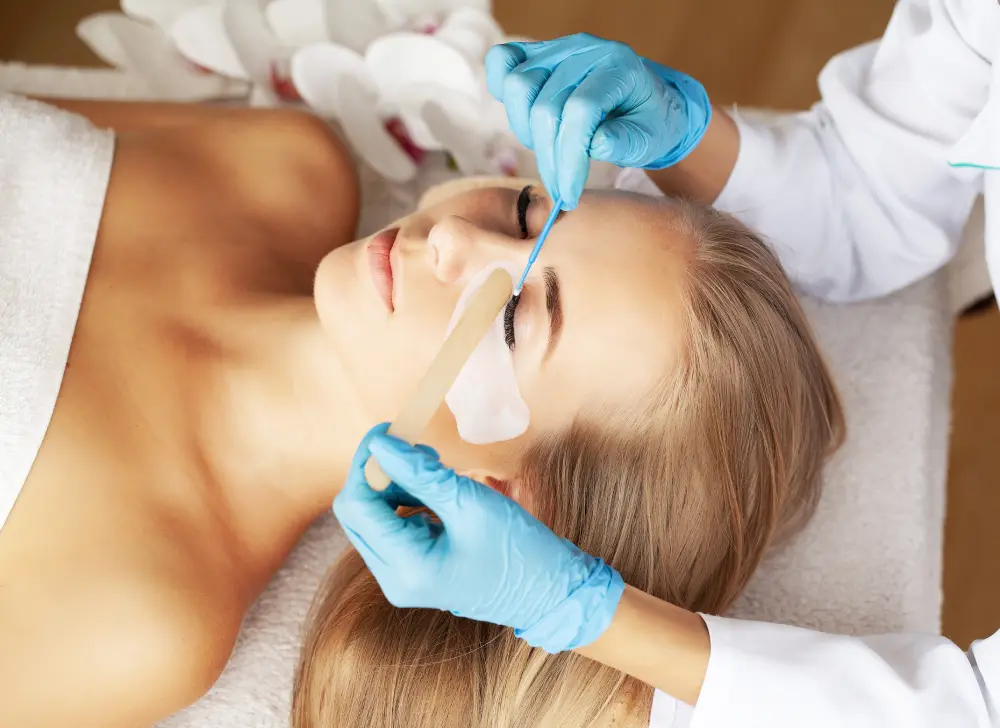 A lash technician consults with a client before a procedure, representing the professional process of conducting an allergy patch test.