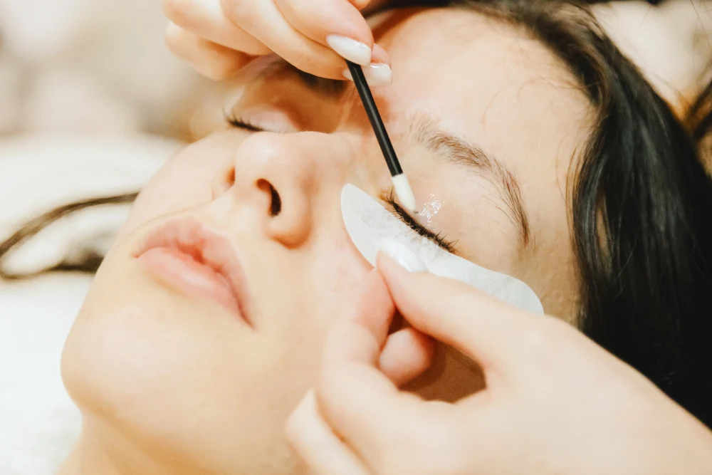 Close-up of a client's eye as a technician cleanses the remaining remover and adhesive from the natural lashes.