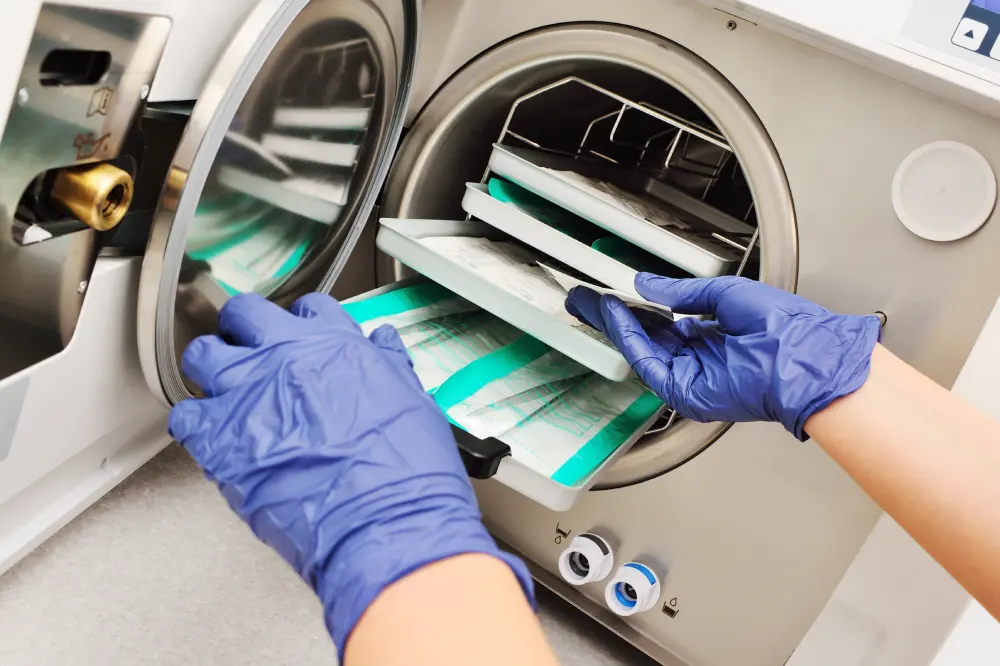 A technician loads packaged instruments into a sterilizer, representing important questions to ask about salon safety and hygiene.