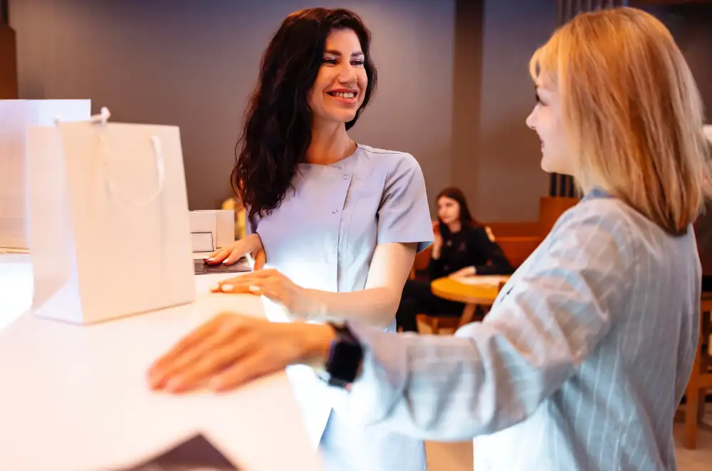 Discussing Your Next Lash Style With a Technician A client at a salon reception desk discusses changing her lash style for more volume with her technician.