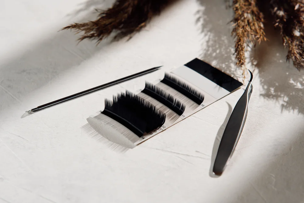 A palette with various eyelash extension strips and professional tools, used for selecting the optimal style and parameters during a consultation.