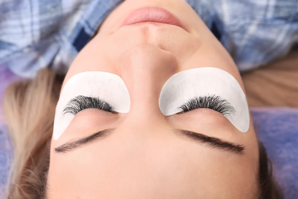 A client lying down with a finished full set of dense and dramatic mega-volume eyelash extensions.