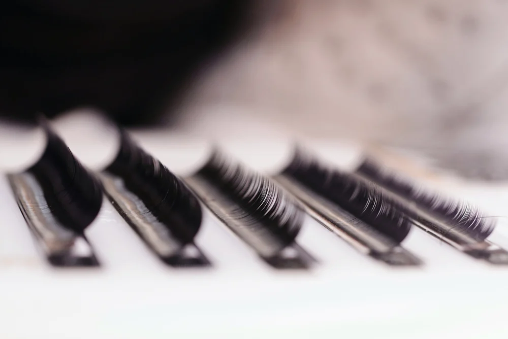 A close-up of PBT eyelash extension fibers on a palette, valued for their ability to mimic the look and feel of natural lashes.