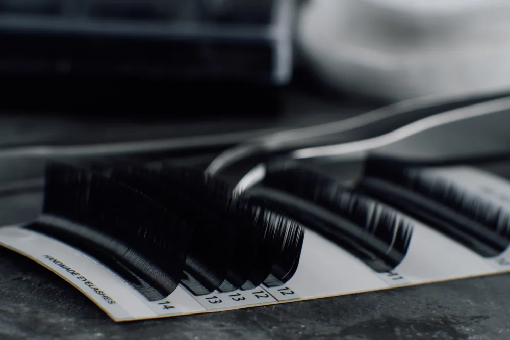 The Importance of Quality Lash Materials and Brands An artistic, black-and-white close-up of high-quality eyelash extension strips on a palette, representing professional-grade materials.