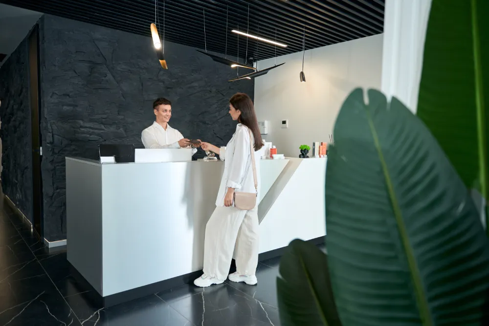 Evaluating a Salon's Cleanliness and Professionalism A client at the reception desk of a modern salon, illustrating a clean and professional environment for lash services.