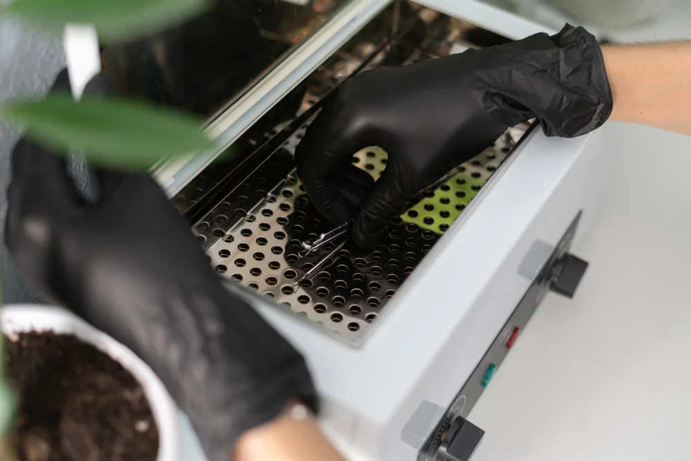 A technician in gloves places a basket of instruments into an autoclave, demonstrating the mandatory sterilization in a professional salon.