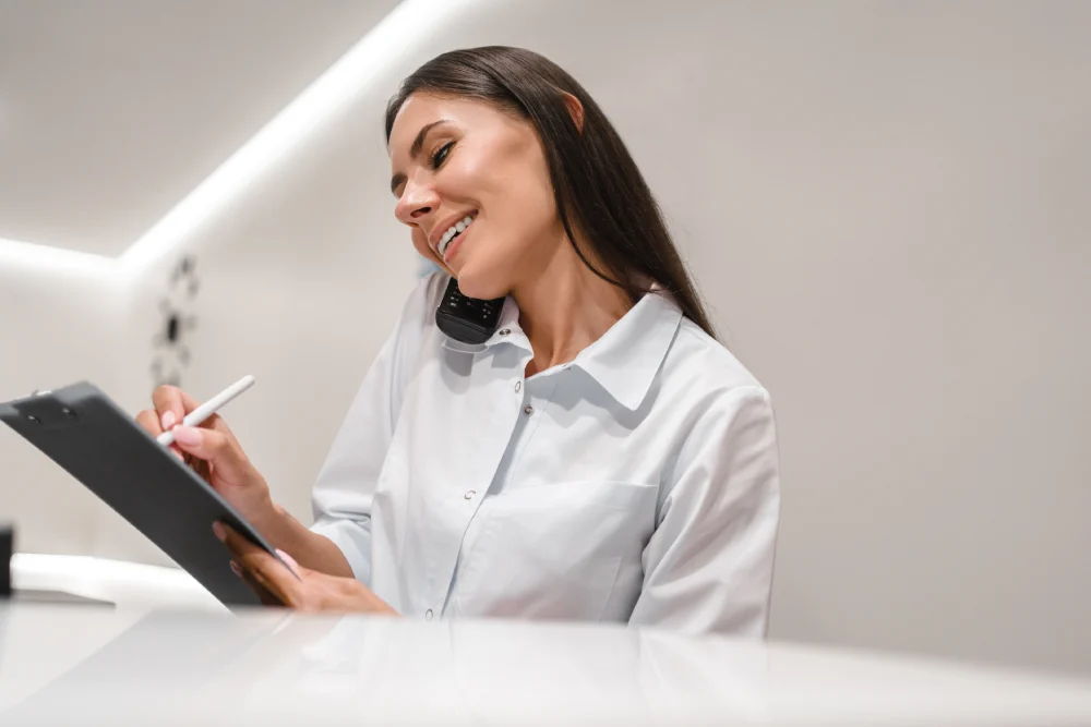 Evaluating Salon Atmosphere and Policies A professional salon receptionist books an appointment while on the phone, representing a salon's welcoming atmosphere and clear policies.