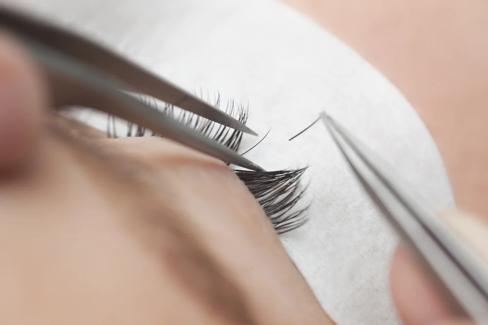 A technician carefully applies a synthetic lash extension, representing the ethical choice of vegan and cruelty-free eyelash products.