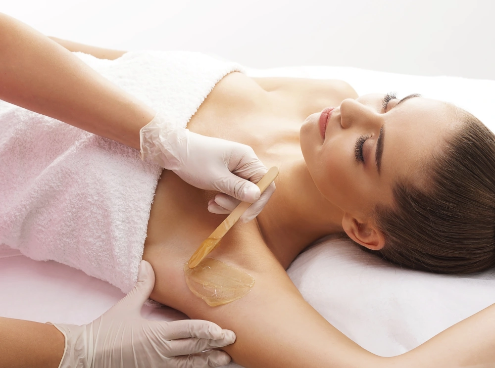 the girl lies on the couch, wax is applied to the armpit area